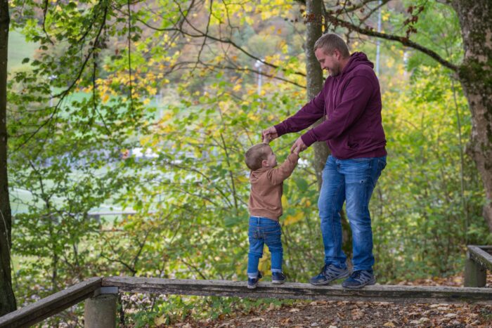 Vater mit Sohn im Wald auf Balken balancierend