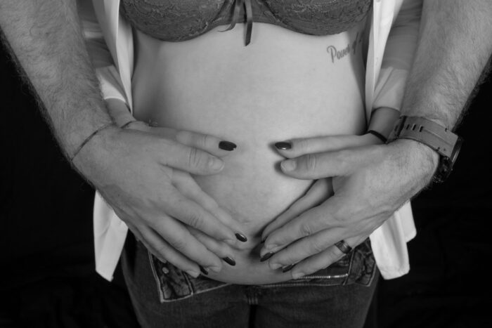 Babybauch, schwarzeiss mit Händen auf dem Bauch