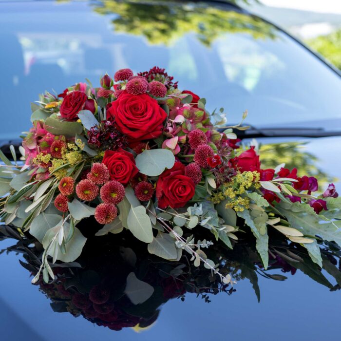 Blumenbouquet auf Motorhaube. Rote Blumen.