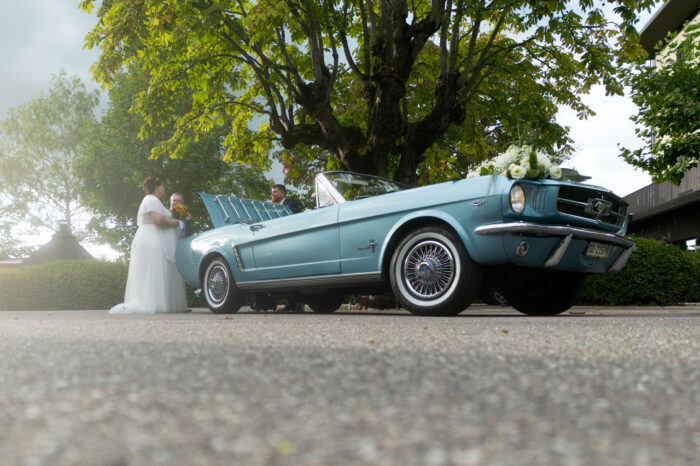 Hochzeitspaar mit blauem Oldtimer Froschperspektive