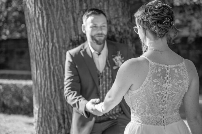 Hochzeitspaar hält sich bei der Hand, Braut im Vordergrund mit Rücken zum Betrachter. Er ist unscharf abgelichtet