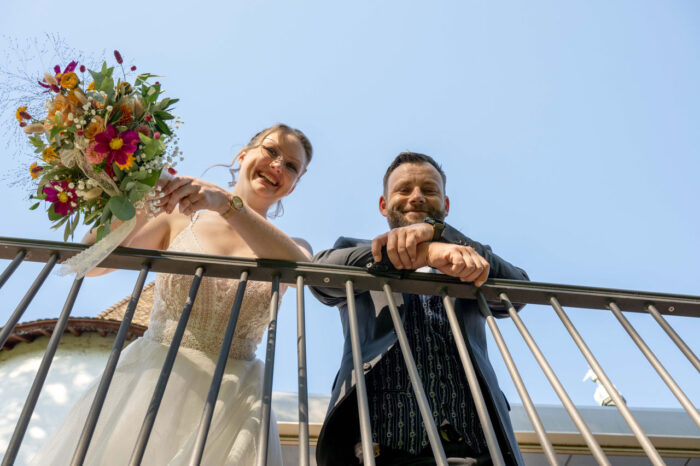 Hochzeitspaar schaut von Balken runter